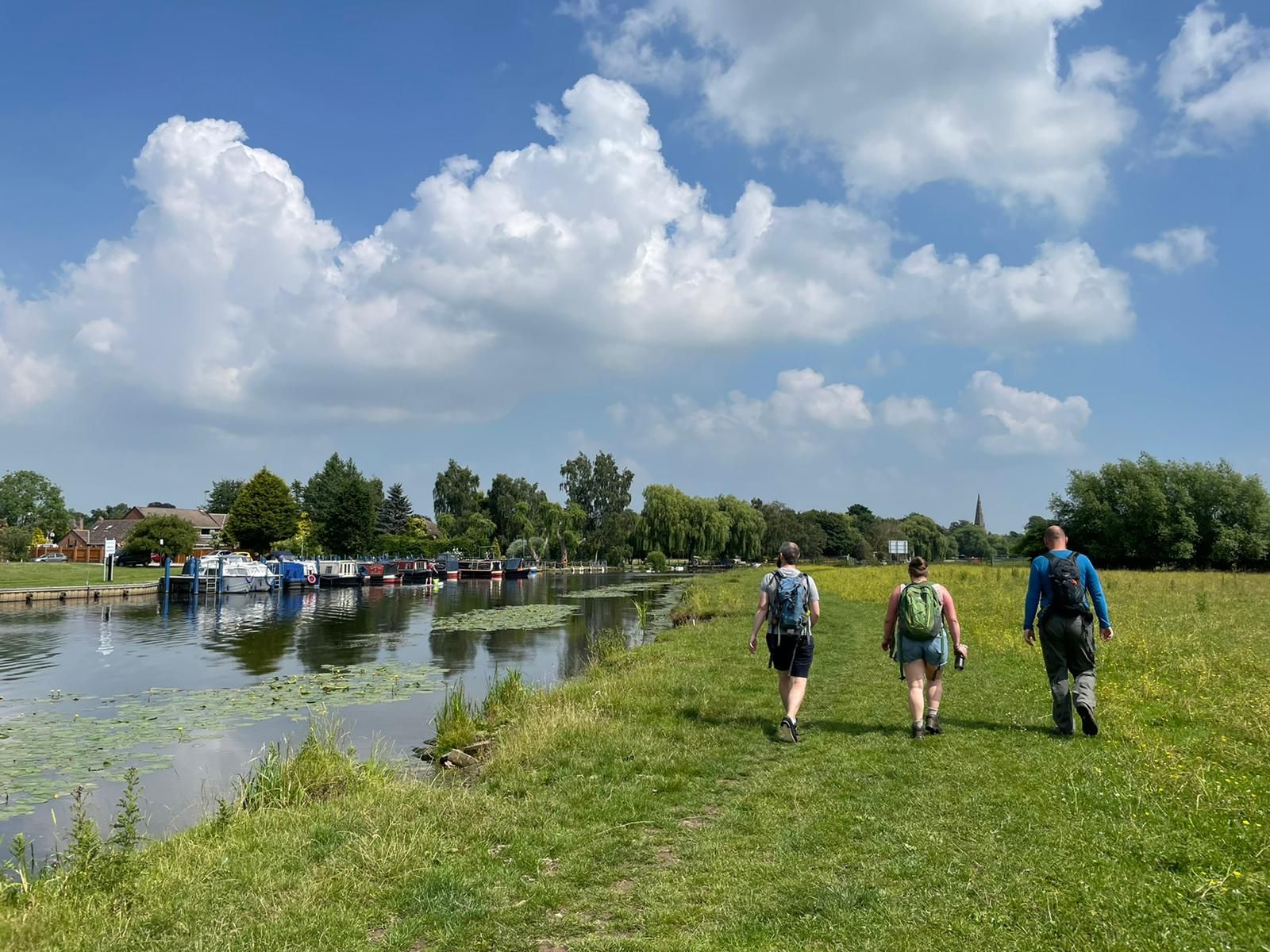 the CWS team walking alongside the river on grass under blue skies