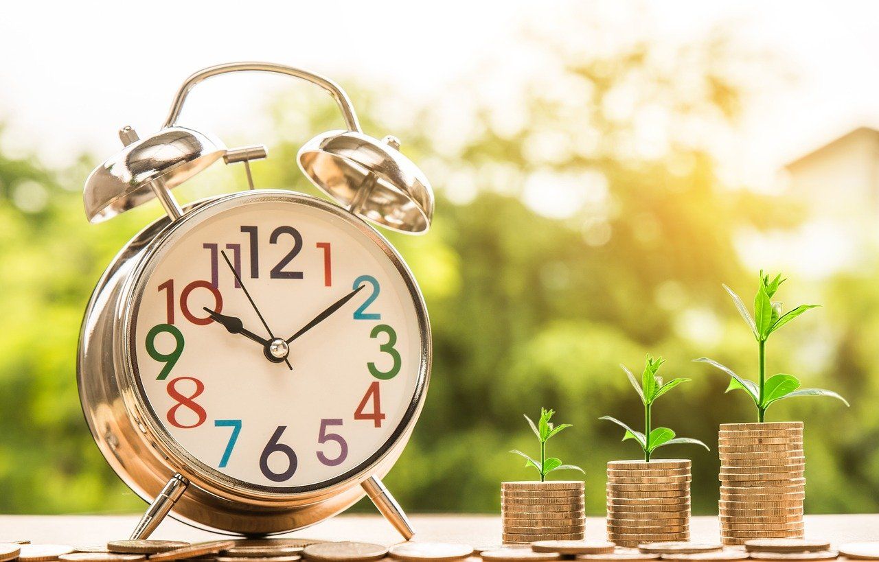 a clock next to piles of coin showing time is money